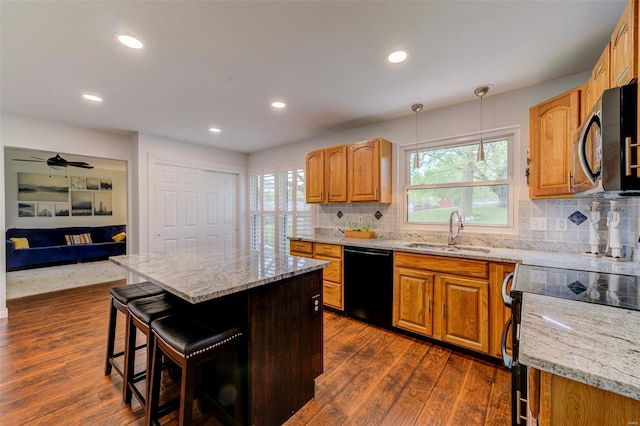 kitchen featuring a sink, range with electric stovetop, light stone counters, dishwasher, and a center island