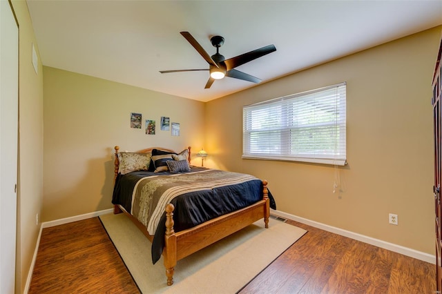 bedroom featuring baseboards, visible vents, ceiling fan, and wood finished floors