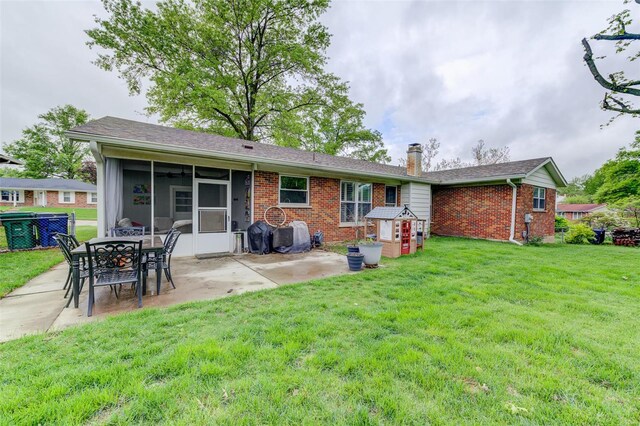 back of house featuring a patio area, brick siding, a yard, a chimney, and a sunroom