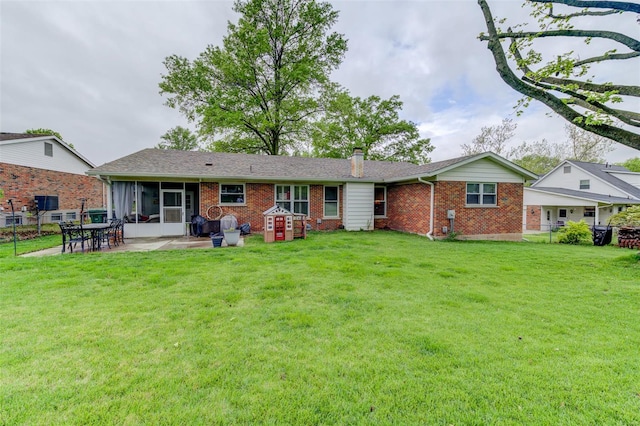 rear view of house featuring a yard, a chimney, brick siding, fence, and a sunroom