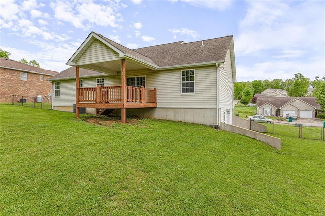 rear view of property featuring a yard, fence, a shingled roof, and a deck