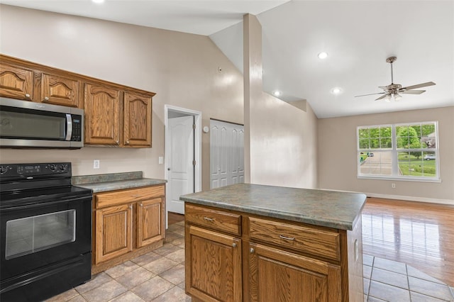 kitchen with brown cabinets, dark countertops, black range with electric stovetop, stainless steel microwave, and ceiling fan