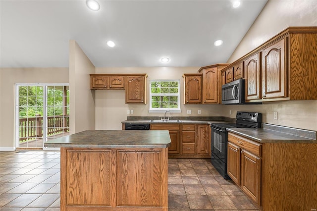 kitchen featuring dark countertops, a center island, brown cabinetry, and black appliances