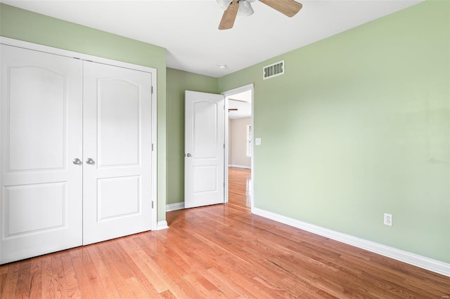 unfurnished bedroom with a closet, light wood-type flooring, visible vents, a ceiling fan, and baseboards