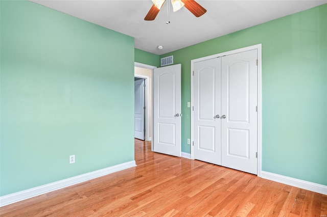 unfurnished bedroom featuring baseboards, a closet, light wood-style flooring, and visible vents