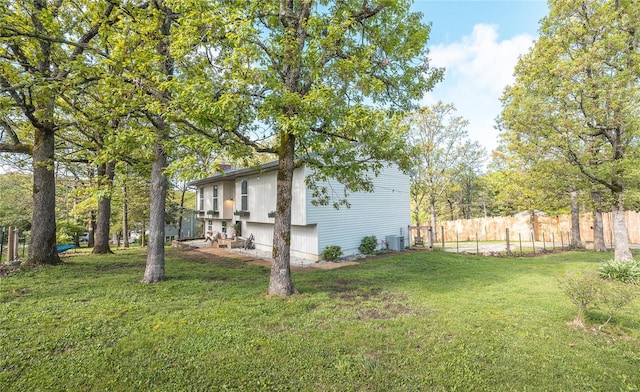 view of property exterior with fence, central AC unit, and a yard