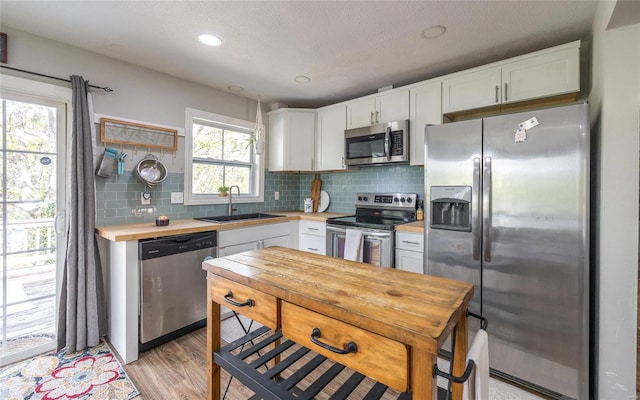 kitchen with a sink, white cabinetry, tasteful backsplash, and stainless steel appliances