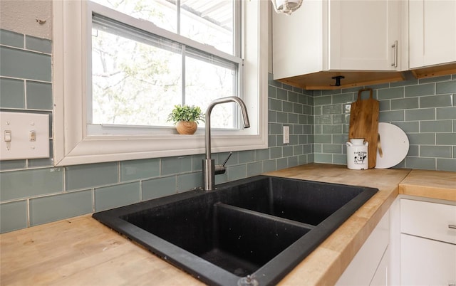 room details with a sink, butcher block counters, white cabinets, and tasteful backsplash