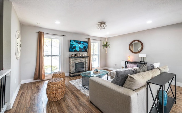 living area featuring baseboards, a fireplace, recessed lighting, and wood finished floors