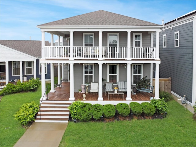 back of property with covered porch, a shingled roof, a yard, and a balcony