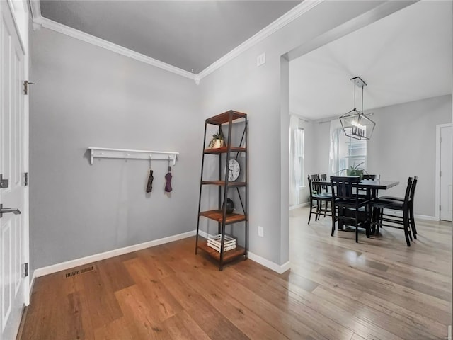 dining area featuring light wood-style floors, baseboards, ornamental molding, and visible vents