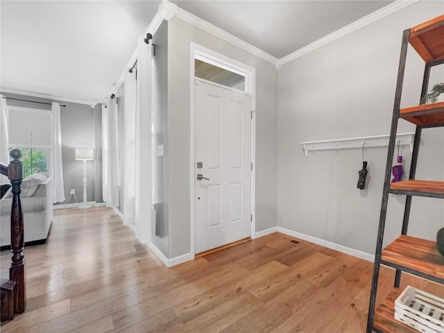 foyer with light wood-style floors, ornamental molding, and baseboards
