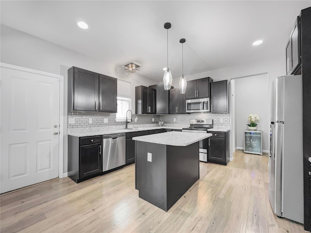 kitchen featuring decorative backsplash, decorative light fixtures, appliances with stainless steel finishes, light countertops, and a sink