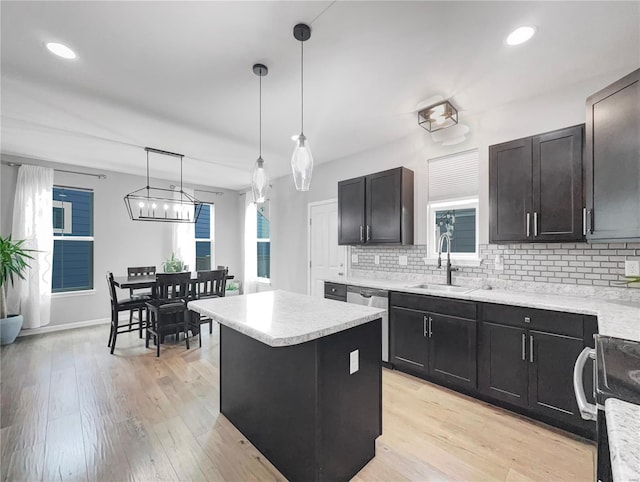kitchen with a kitchen island, tasteful backsplash, light wood-type flooring, a sink, and light countertops