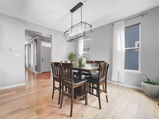 dining room featuring light wood-style floors, baseboards, a notable chandelier, and visible vents