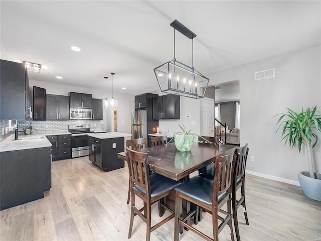 dining area featuring an inviting chandelier, light wood-style flooring, recessed lighting, baseboards, and visible vents