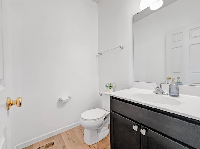 bathroom featuring vanity, visible vents, wood finished floors, toilet, and baseboards