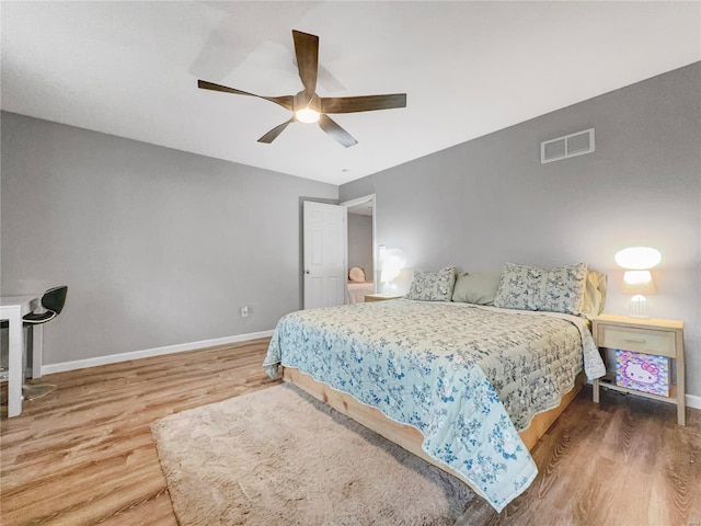 bedroom with baseboards, a ceiling fan, wood finished floors, and visible vents