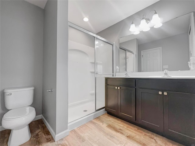 full bathroom featuring double vanity, wood finished floors, toilet, a shower stall, and a sink