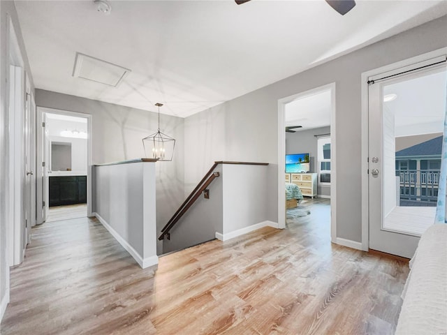 hallway with baseboards, an upstairs landing, an inviting chandelier, and light wood finished floors