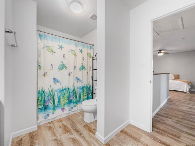bathroom featuring baseboards, wood finished floors, toilet, and a shower with curtain