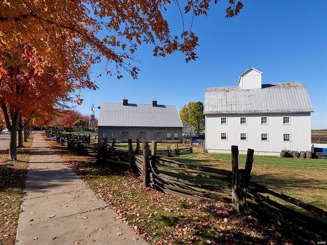 view of property exterior with a yard, a barn, fence, and an outbuilding