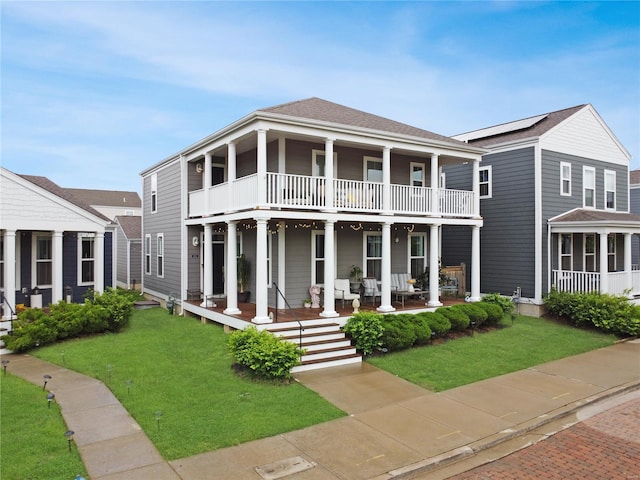 neoclassical home featuring a porch, a balcony, and a front lawn