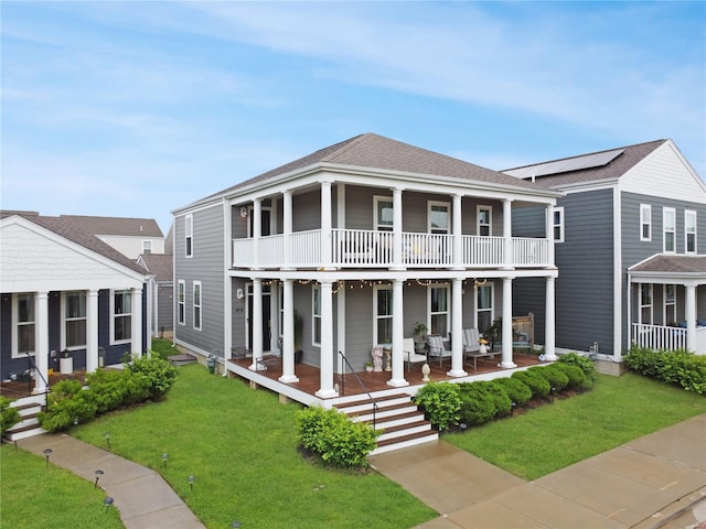 view of front of house featuring a shingled roof, a front yard, a porch, and a balcony