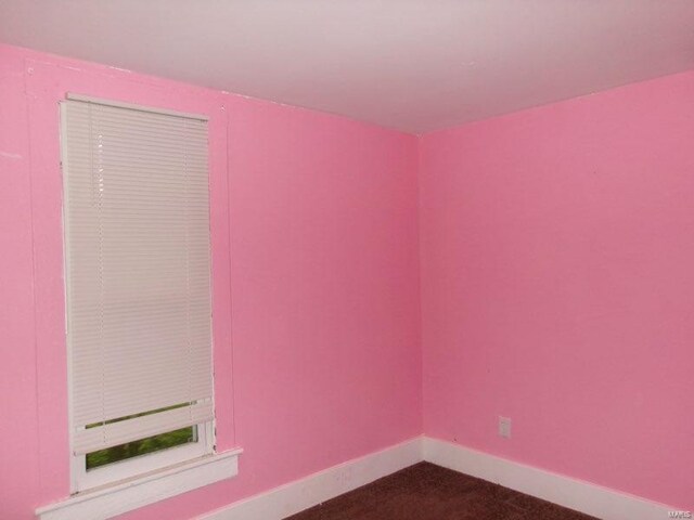 empty room with baseboards and dark colored carpet