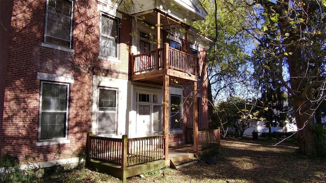 back of property with brick siding and a balcony