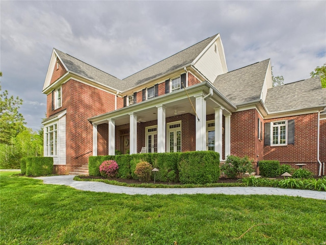 view of front of property featuring a shingled roof, a front yard, and brick siding