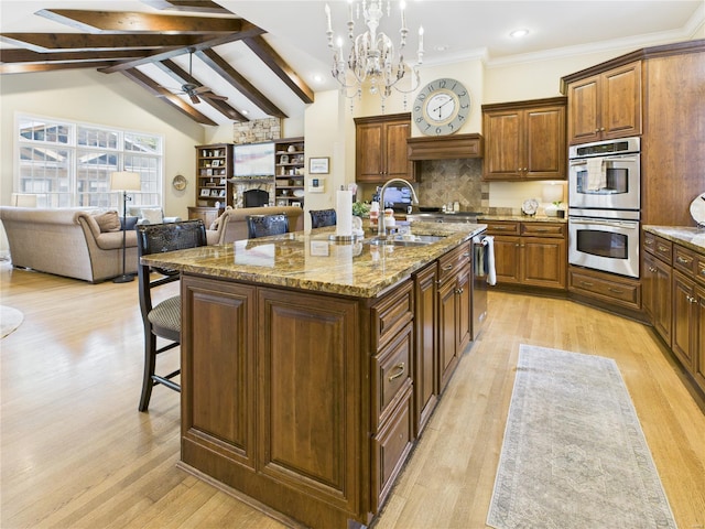 kitchen with a fireplace, a kitchen breakfast bar, light wood-type flooring, a sink, and appliances with stainless steel finishes