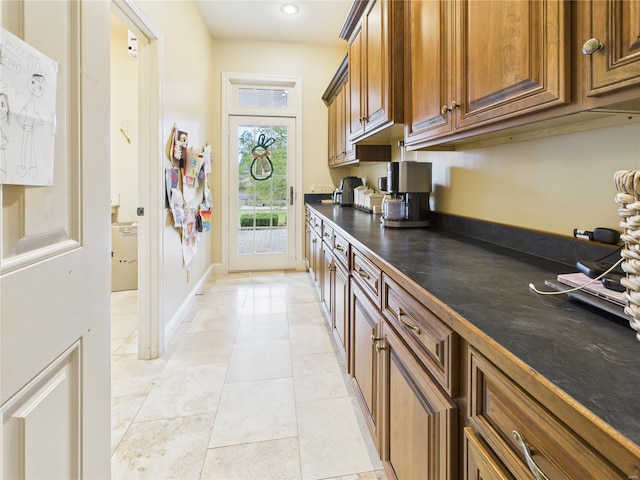 kitchen with brown cabinetry, recessed lighting, light tile patterned flooring, and dark countertops