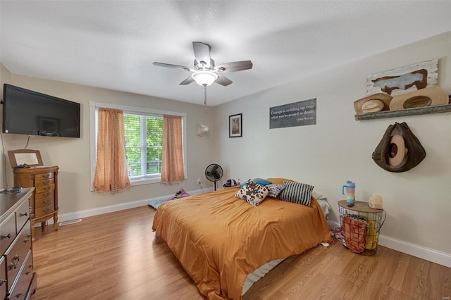 bedroom with baseboards, ceiling fan, and light wood finished floors