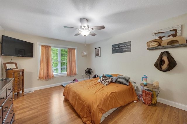 bedroom featuring baseboards, ceiling fan, and light wood-style floors