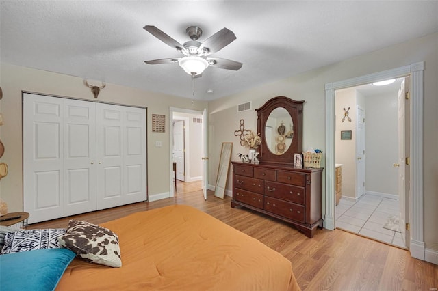 bedroom with ceiling fan, light wood-style flooring, baseboards, visible vents, and a closet