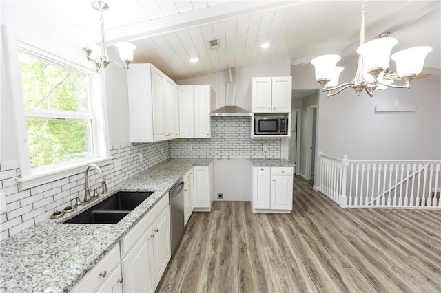 kitchen with wall chimney range hood, visible vents, a sink, a chandelier, and stainless steel appliances