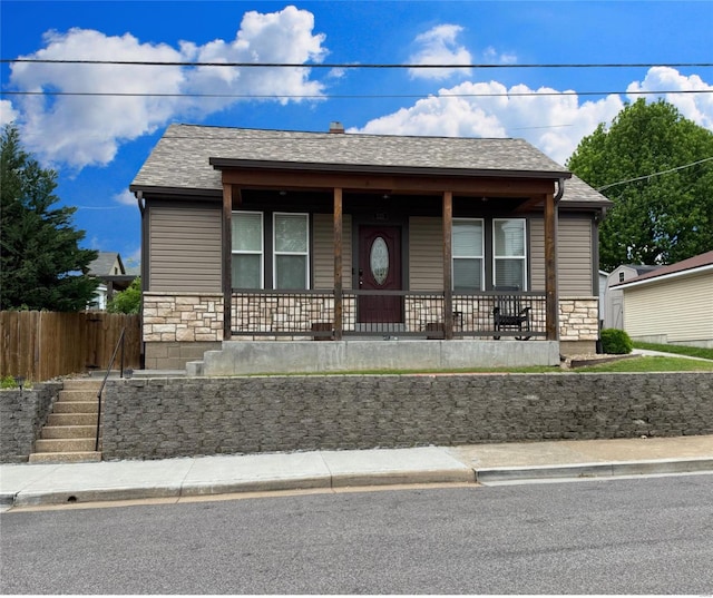 bungalow with fence, a shingled roof, stone siding, stairway, and covered porch