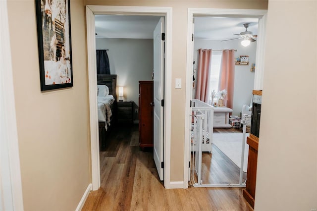 corridor featuring light wood-style floors and baseboards