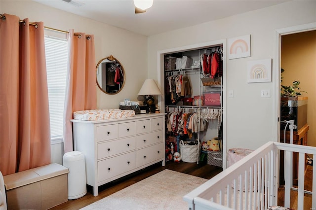 bedroom with a closet, a crib, wood finished floors, and visible vents