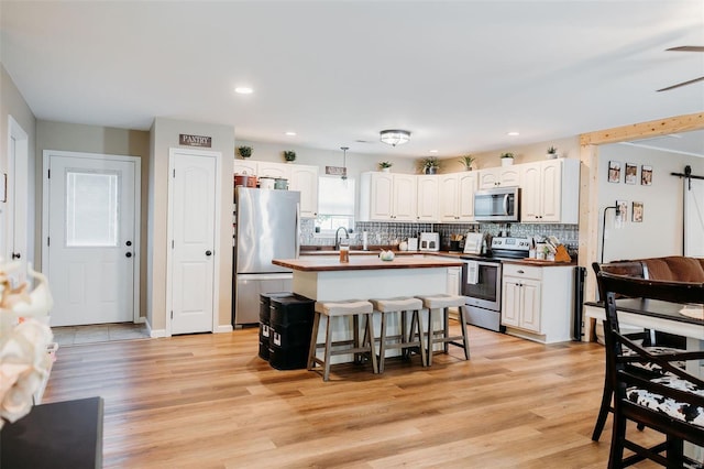 kitchen with butcher block counters, backsplash, white cabinets, and stainless steel appliances