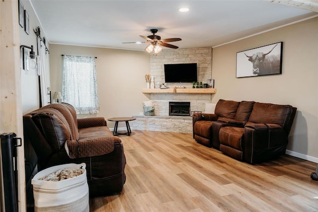 living area featuring crown molding, ceiling fan, a stone fireplace, and wood finished floors