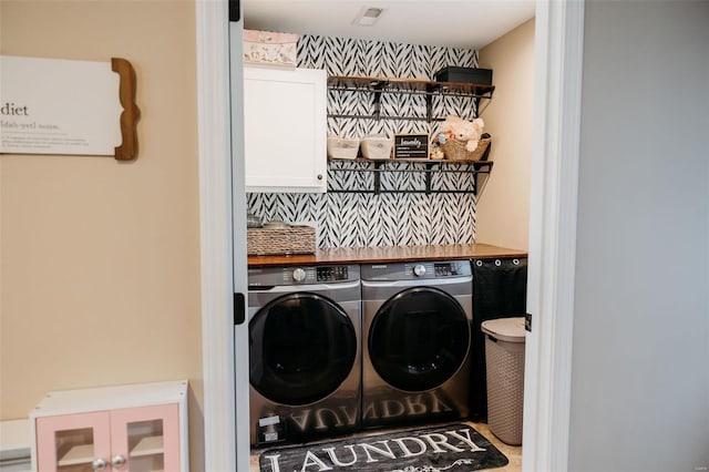 washroom featuring visible vents, washer and clothes dryer, and cabinet space