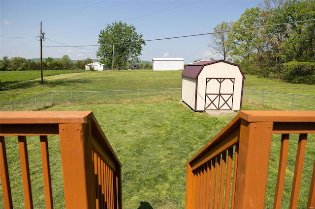 view of yard featuring a fenced backyard, an outbuilding, a storage shed, and a rural view