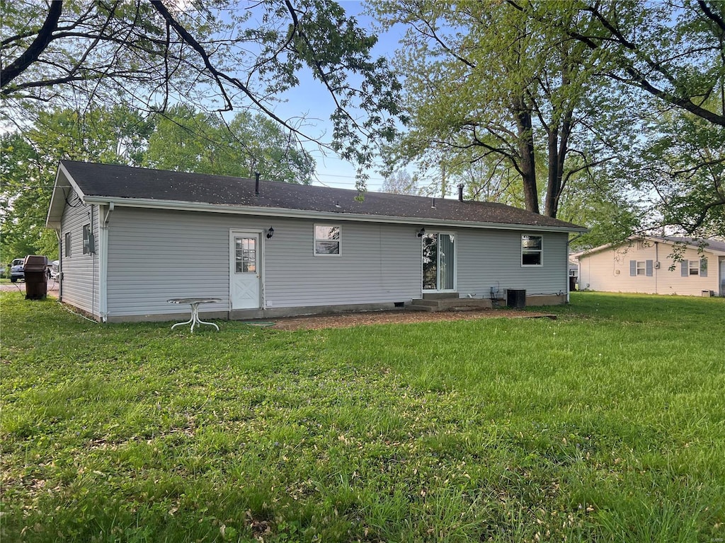 rear view of property with central air condition unit, a yard, and entry steps