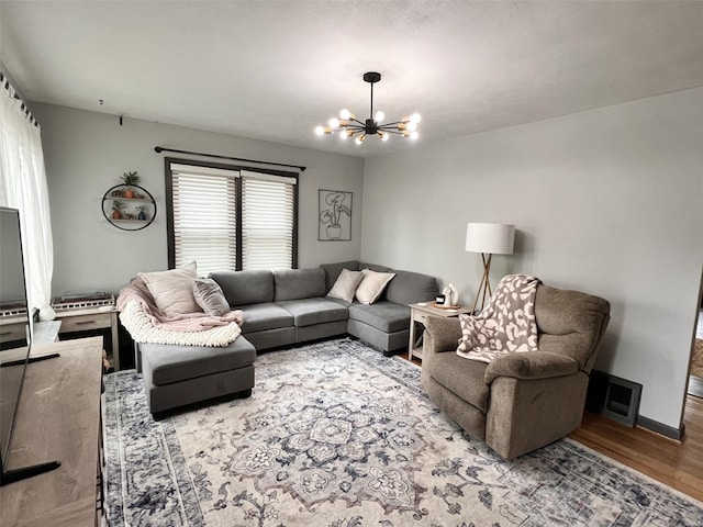 living area featuring baseboards, a notable chandelier, visible vents, and wood finished floors