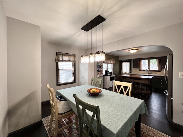 dining space featuring dark wood-style flooring and arched walkways