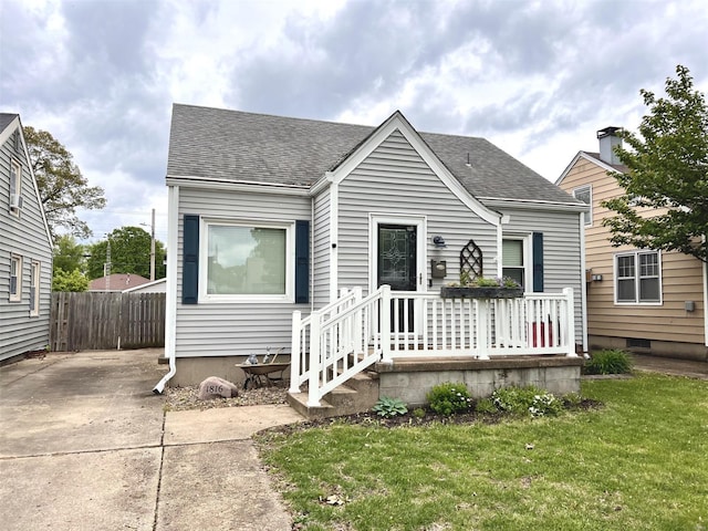 view of front of property with roof with shingles, fence, and a front yard