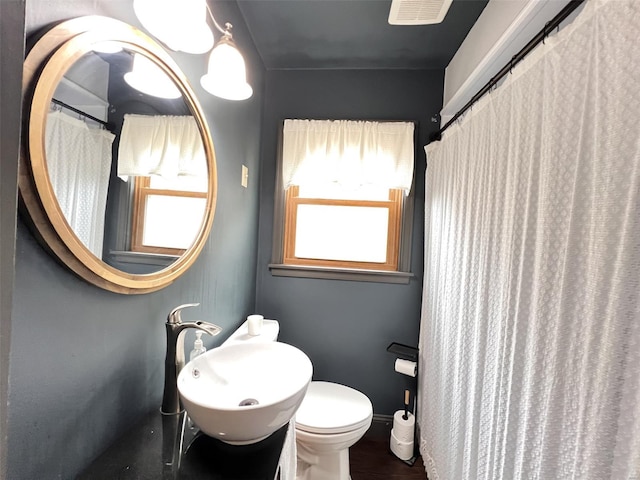 bathroom with toilet, visible vents, a sink, and wood finished floors