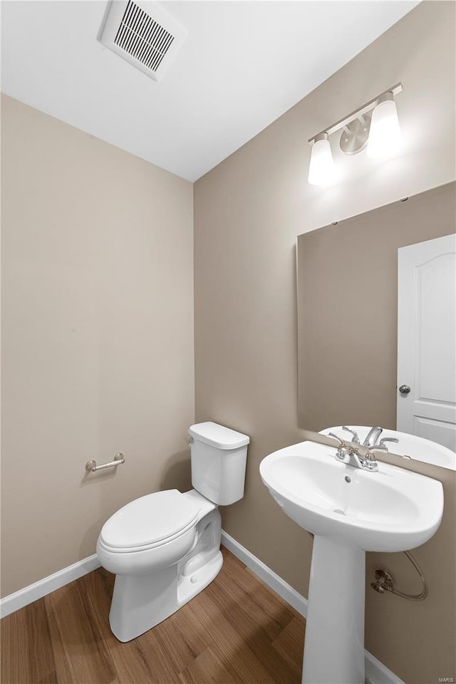 bathroom featuring visible vents, wood finished floors, a sink, baseboards, and toilet